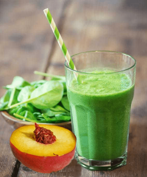 Peach smoothie with spinach and peach on table