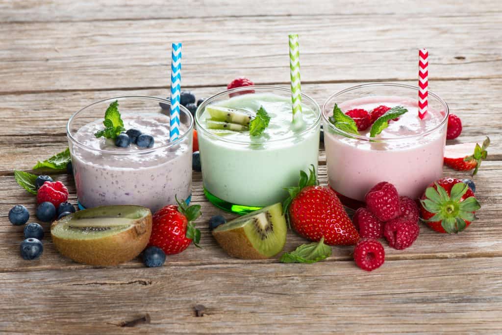 colorful smoothies with different types of fruit on wooden background