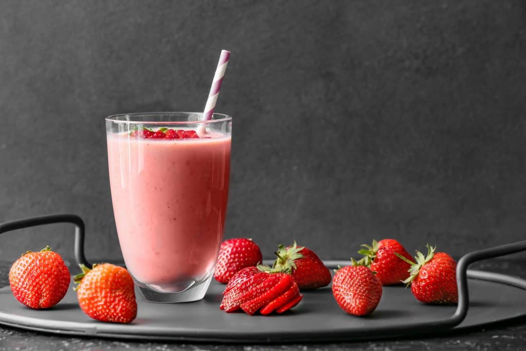 Glass of tasty strawberry smoothie on dark background