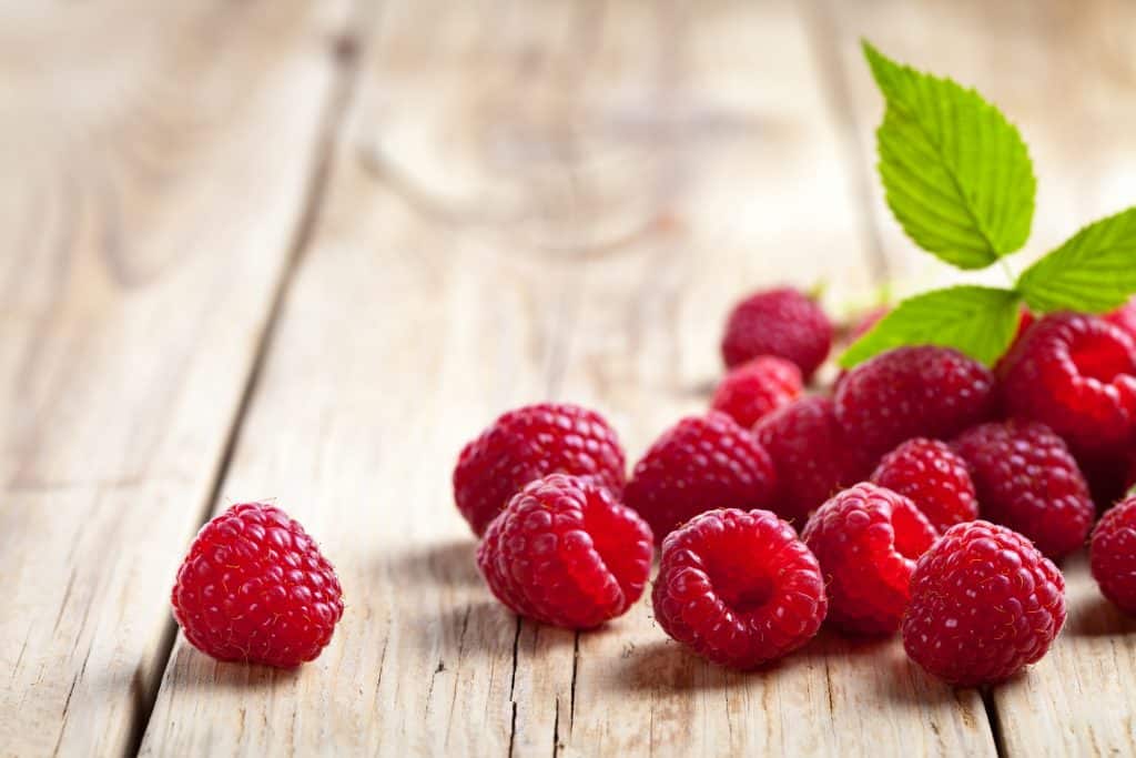 Raspberries with leaf on wooden table background. 