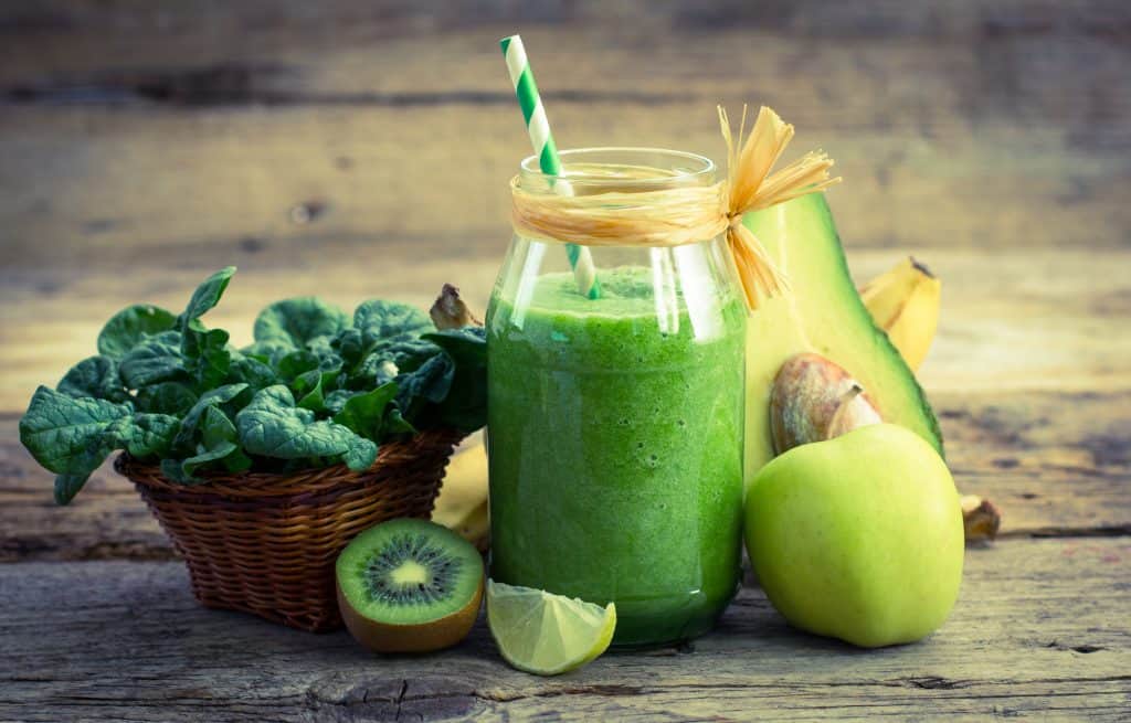 green smoothie with healthy ingredients surrounding