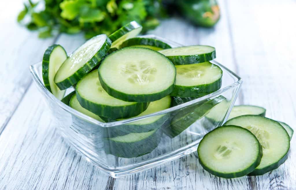 sliced cucumber in glass bowl on wooden background