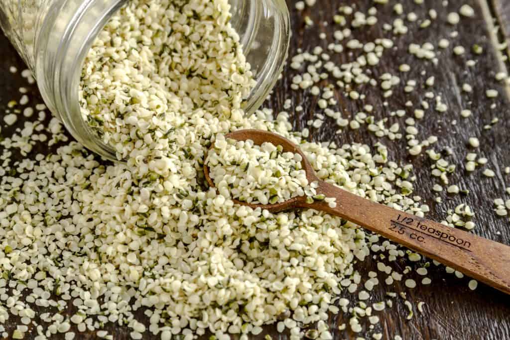 hemp seeds pouring on table with wooden spoon