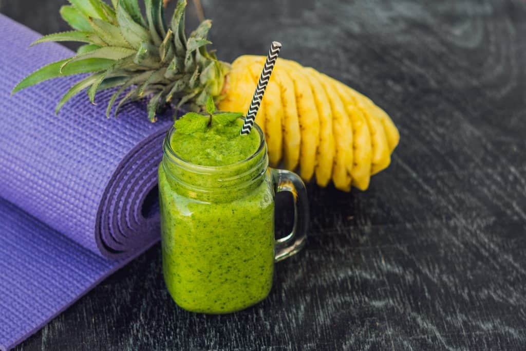 tropical smoothie with pineapple and yoga mat on table.