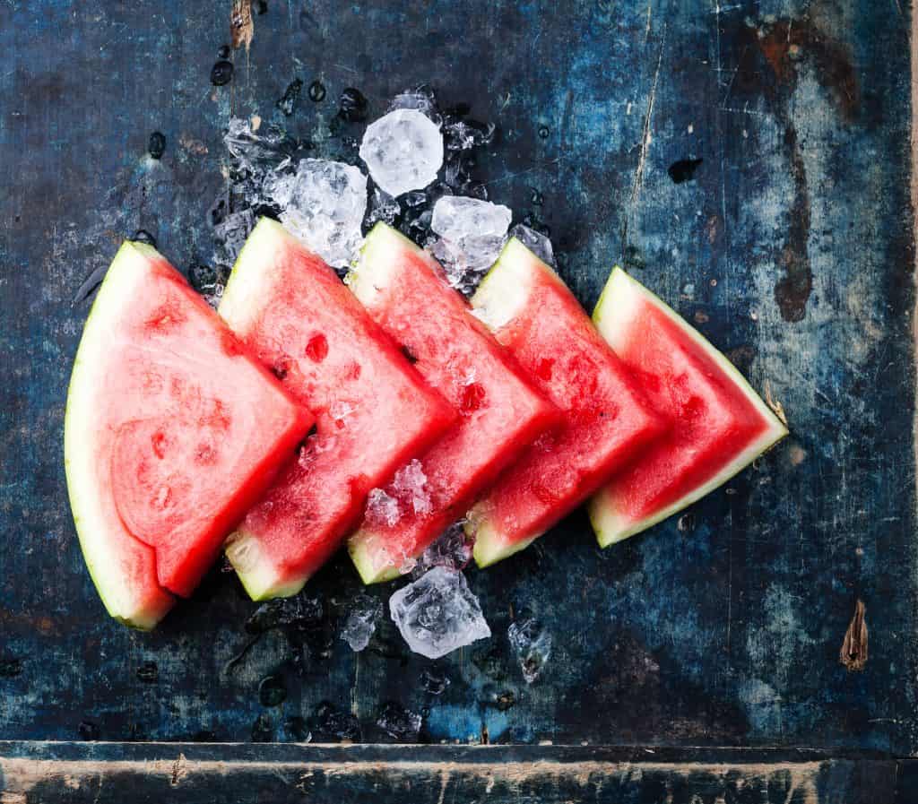 Watermelon slices and ice on blue background