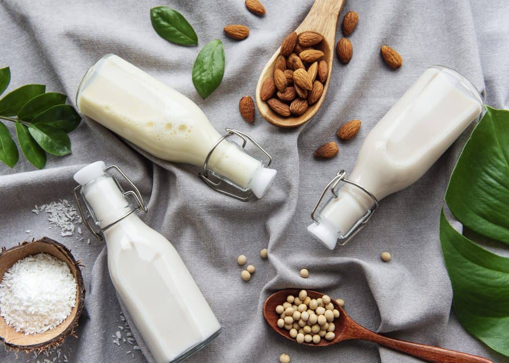 Bottles with different plant milk - soy, almond and oat milk.