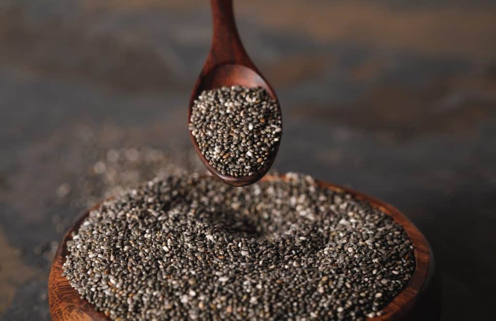 chia seeds in wooden bowl on dark background with spoon