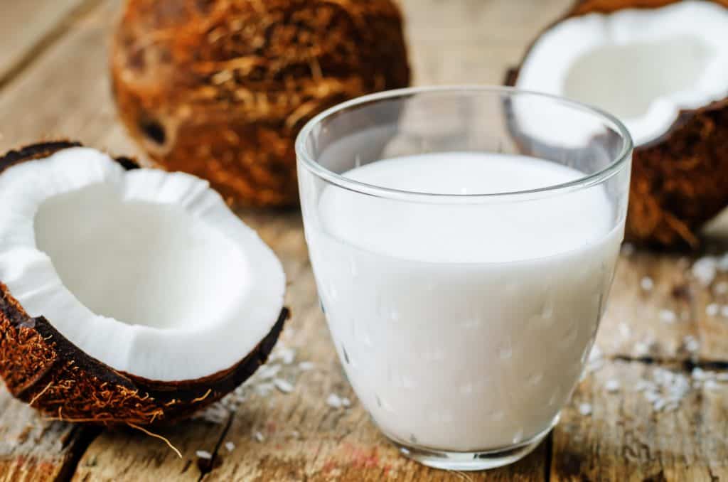 coconut milk and coconuts on a dark wood background.