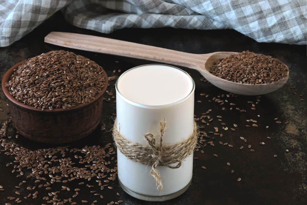 flax milk and seeds on dark wooden background