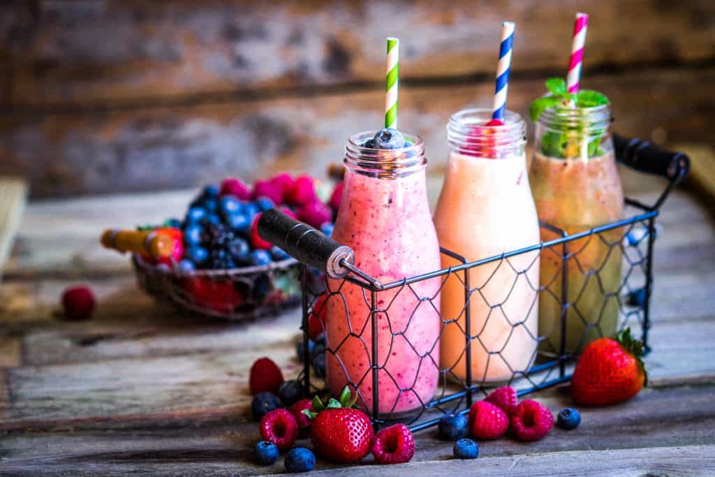 Three smoothies in bottles on wooden background