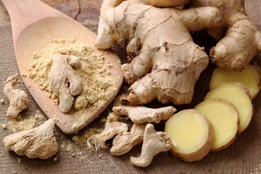 fresh ginger root and powder on a wooden board