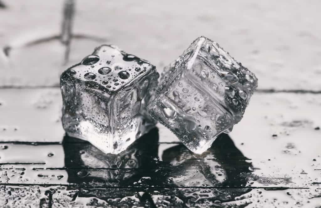 close up of ice cubes on wet wooden background