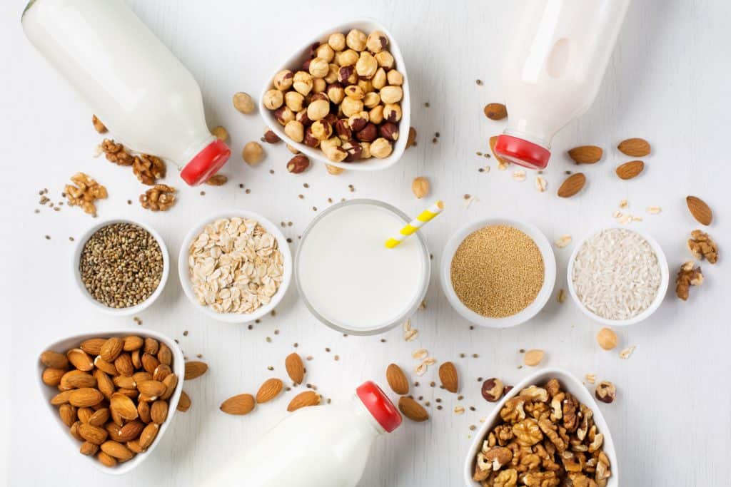 Fresh vegan alternative nut milk in glass bottles on white background. Healthy plant food concept, top view