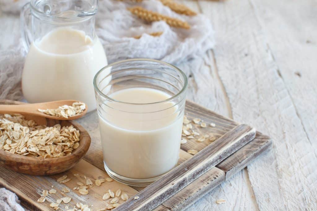 Vegan oat milk, non dairy alternative milk in a glass close up