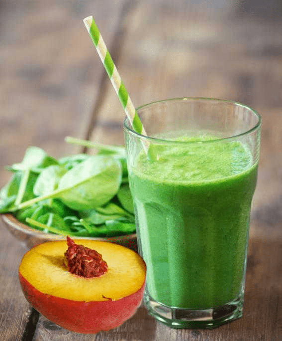 smoothie with spinach and peach on wooden background