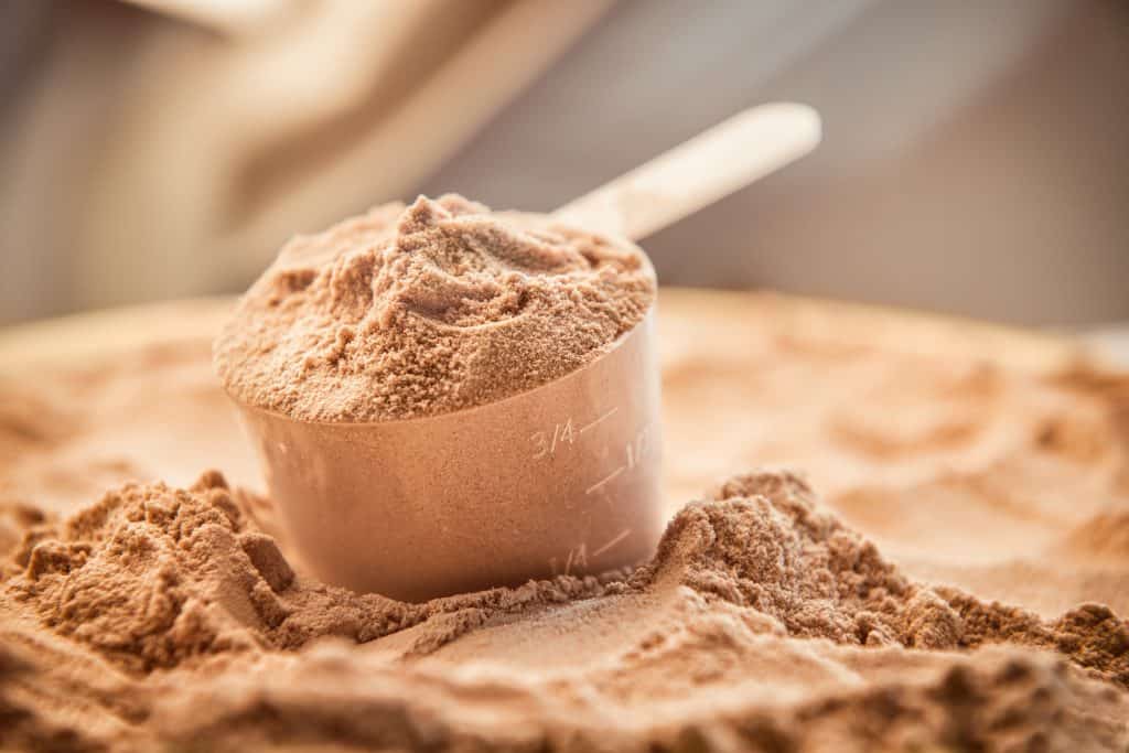 scoop of chocolate protein powder sitting on powder