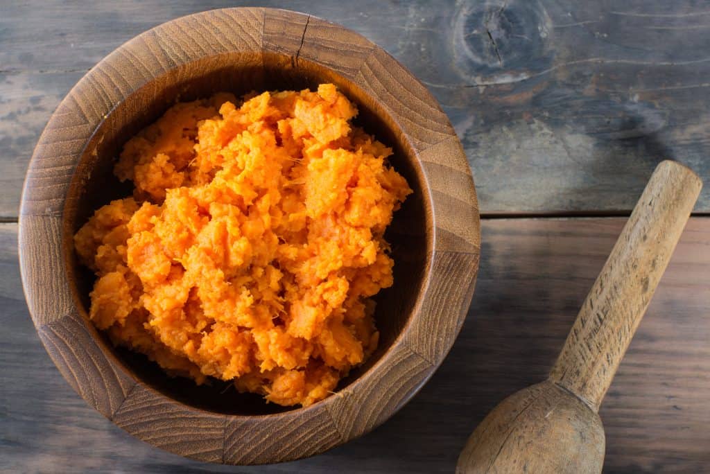 A bowl of orange organic mashed sweet potato vegetable.