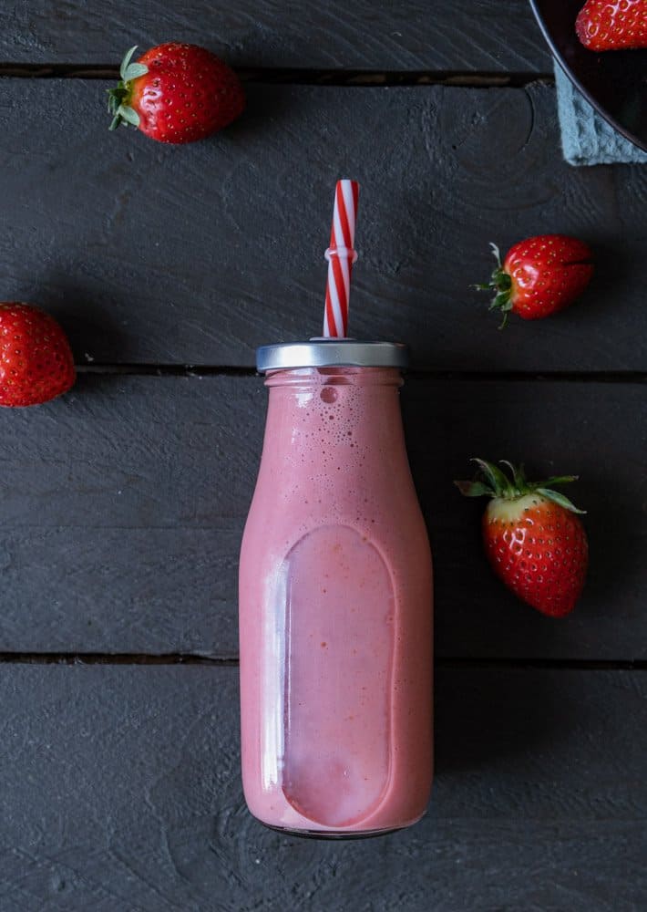 strawberry detox smoothie in a glass jar with strawberries surrounding