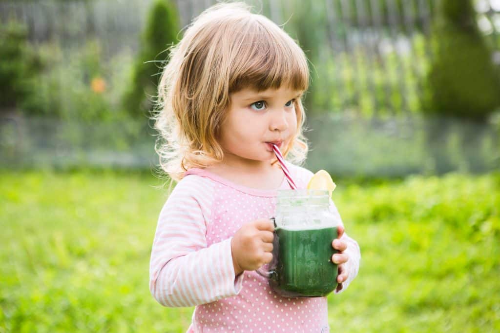 toddler drinking a green smoothie