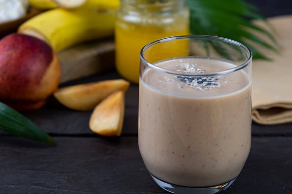 banana peach smoothie with ingredients in background