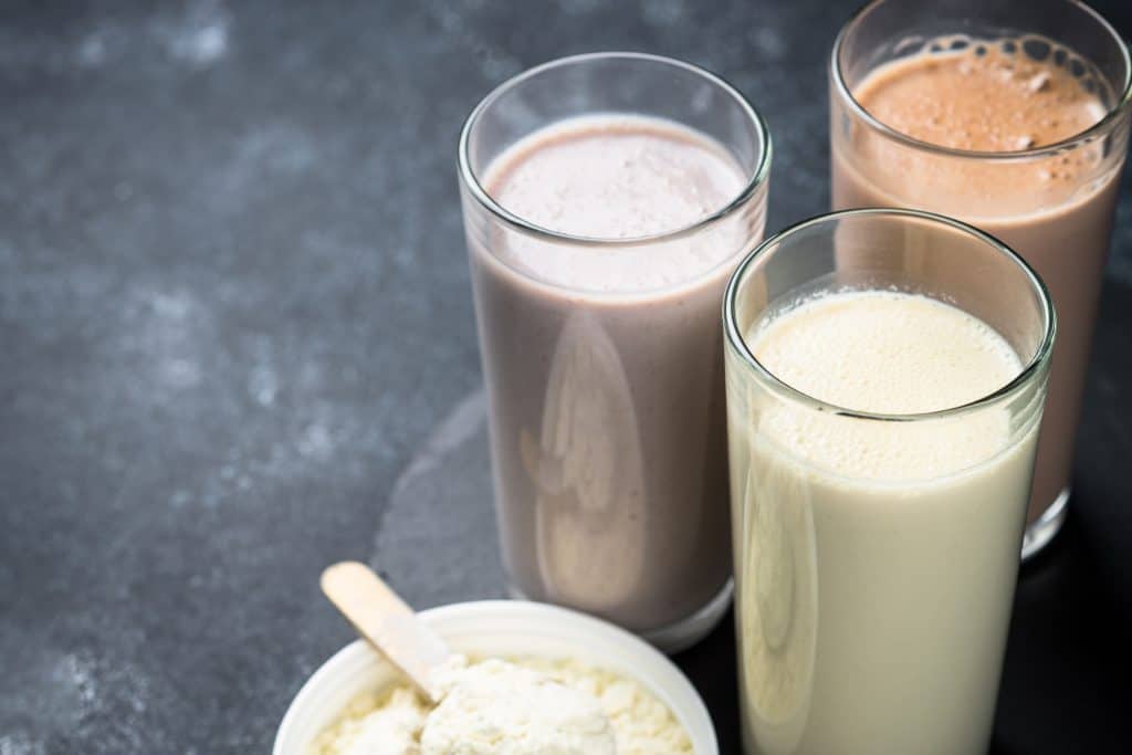 Variety of protein shakes with powder on dark background