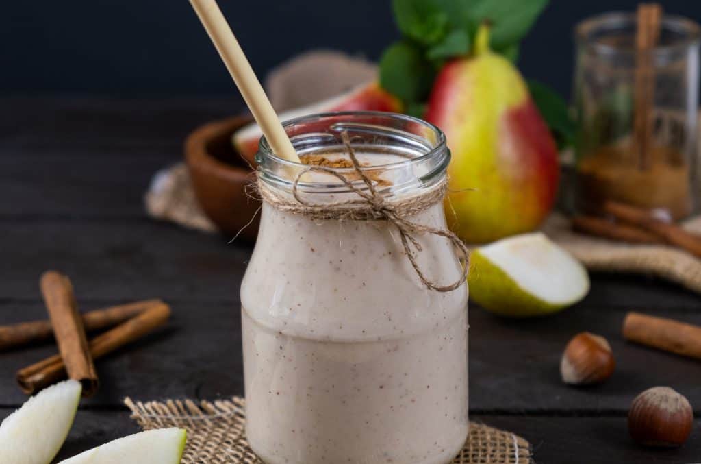 pear yogurt smoothie in glass with ingredients in background
