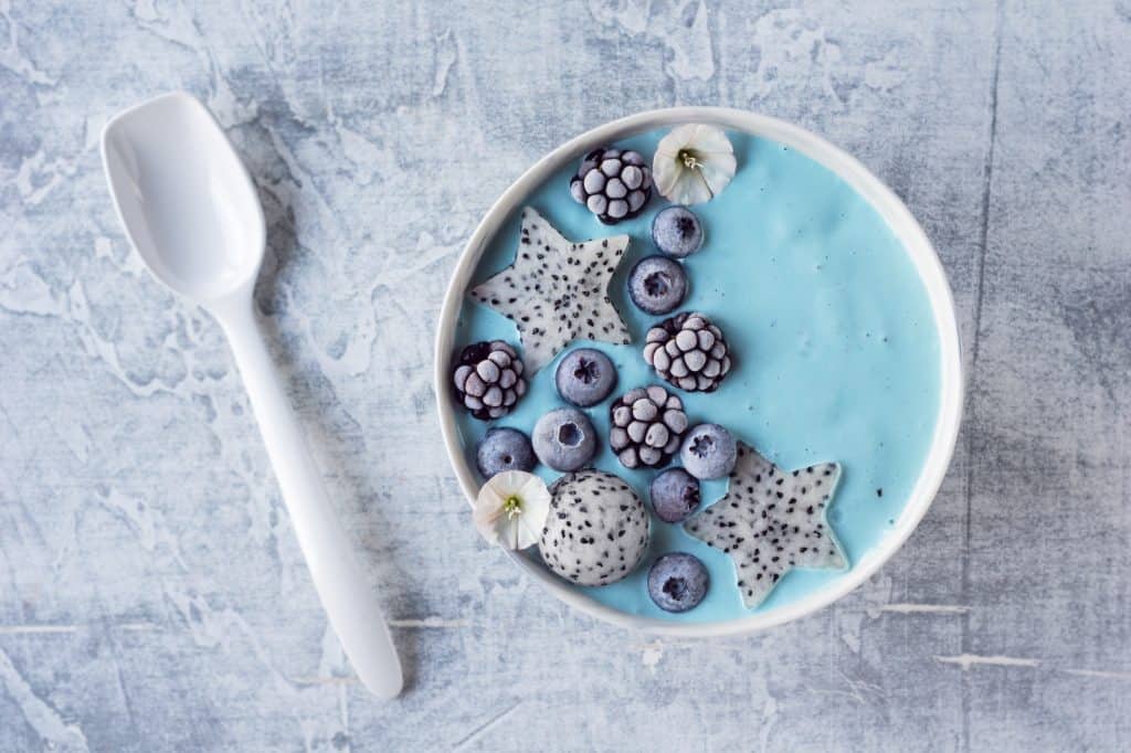 blue smoothie bowl on concrete background with spoon