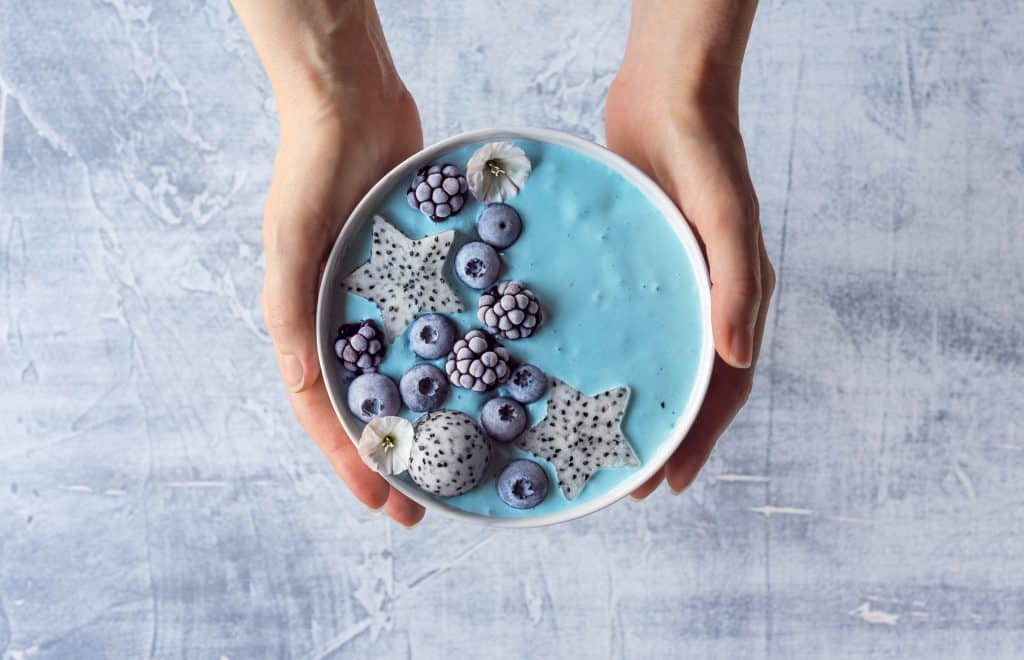 blue smoothie bowl held in woman's hands 
