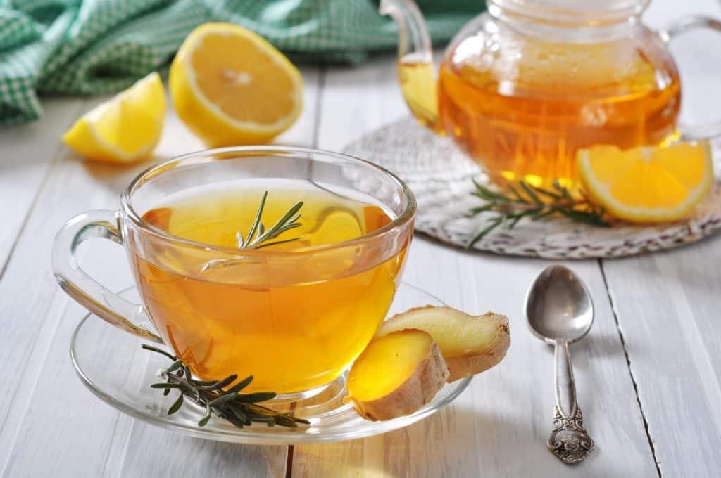 Ginger tea with lemon and rosematy in glass cup closeup.