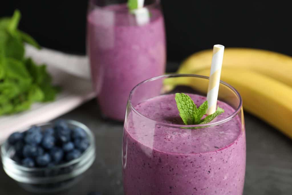 Delicious blueberry smoothie served on grey table, closeup