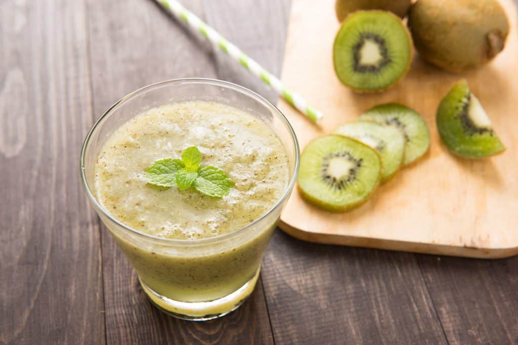 kiwi smoothie with fresh fruits on wooden table.