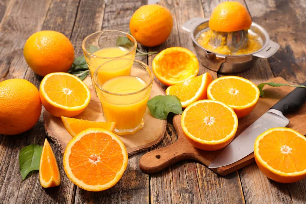 fresh oranges and juice on a wooden background