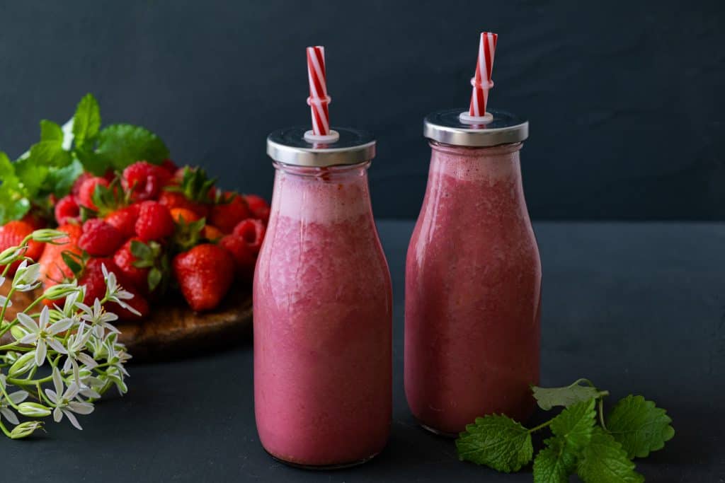 raspberry smoothies without banana in glass jars on dark background
