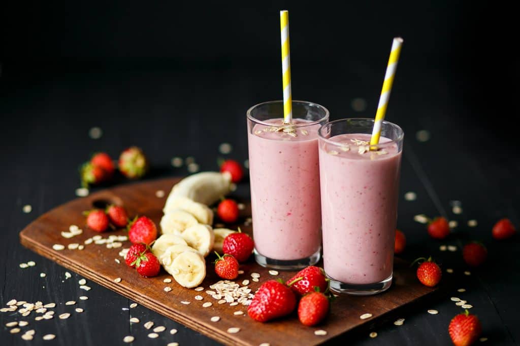 Strawberry and banana smoothie in glasses on black background