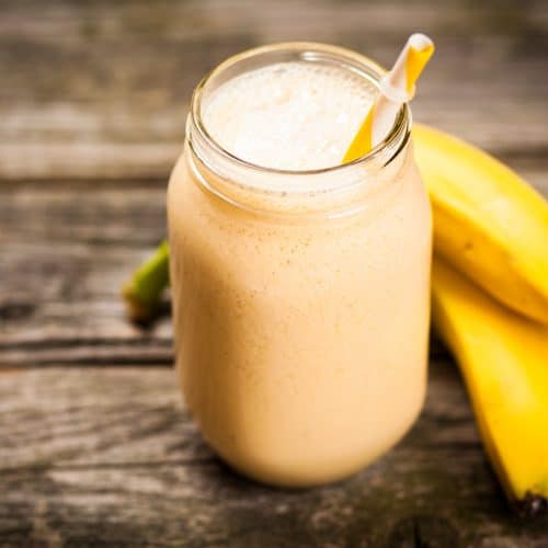 banana smoothie in glass on wooden table