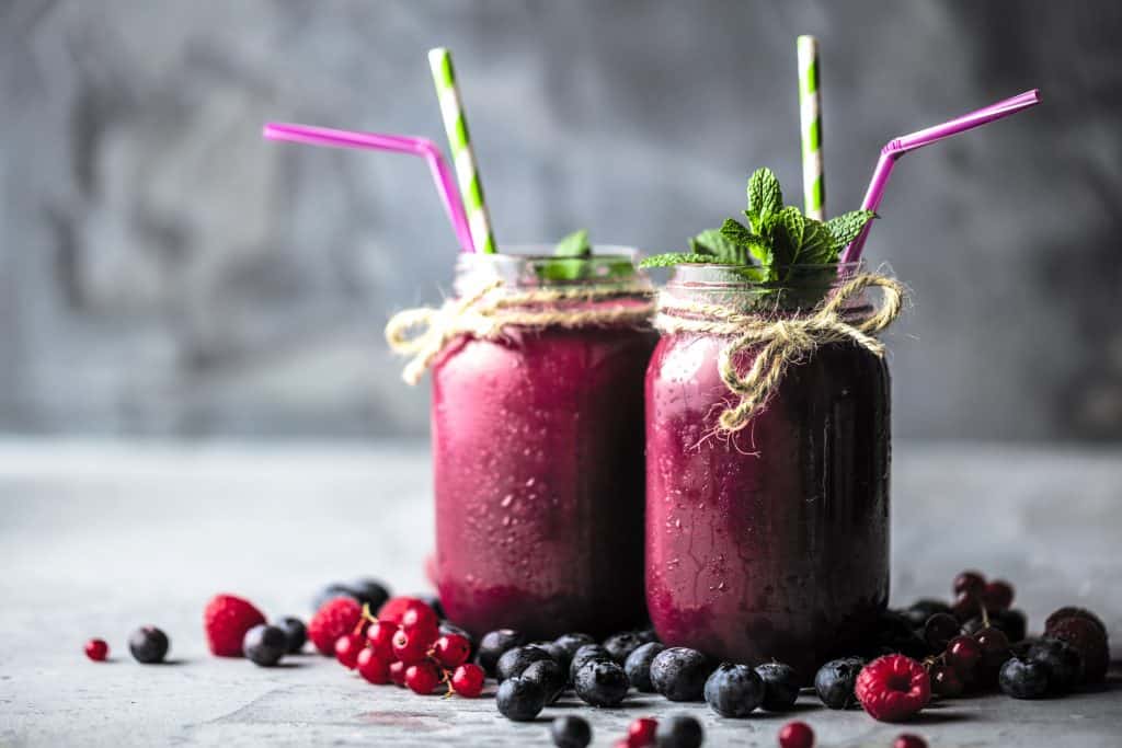 Healthy smoothies with fresh ingredients on a kitchen board.