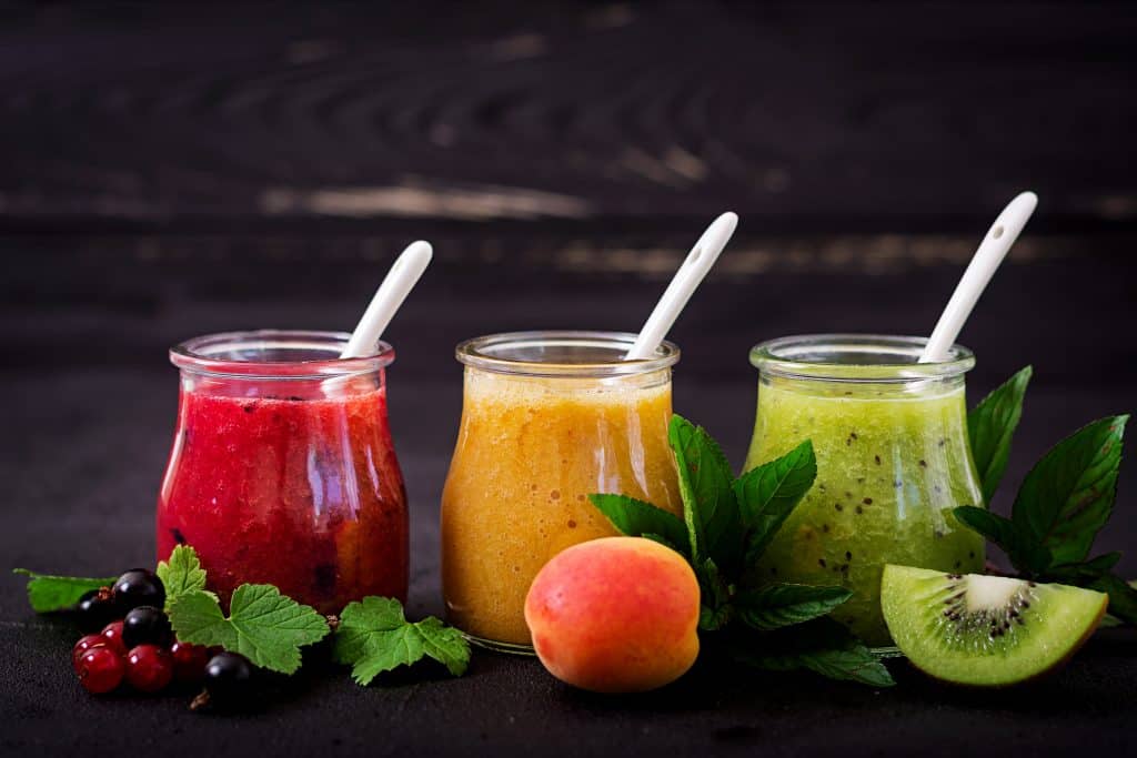 three fruit smoothies on dark wooden background