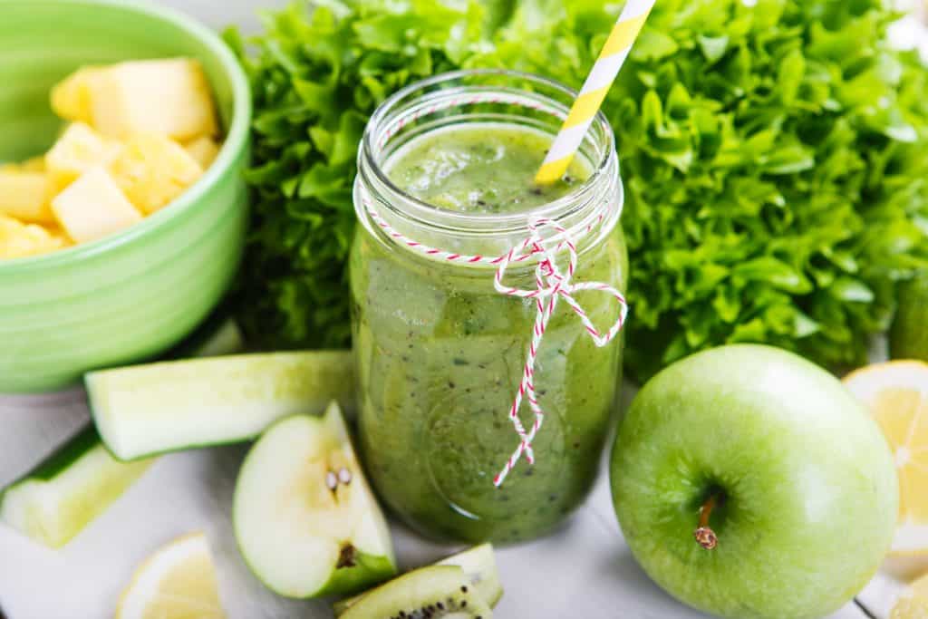 Green smoothie for diabetics in glass jar with ingredients surrounding
