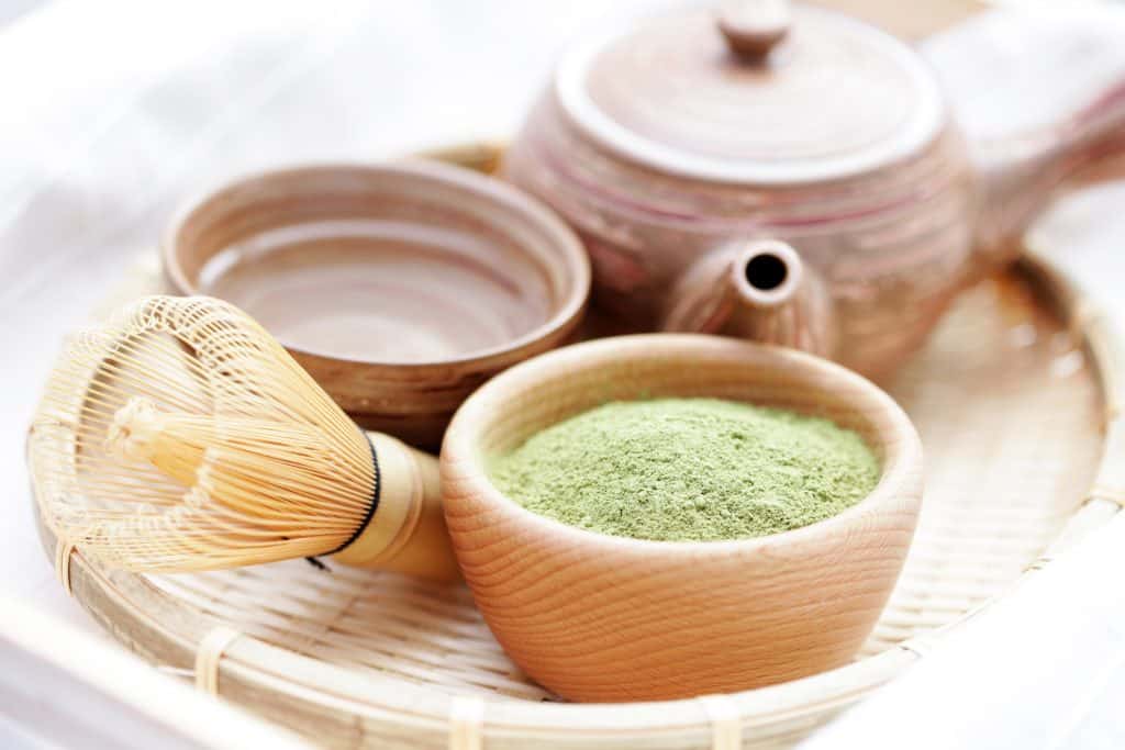 powdered matcha tea with bamboo whisk and tea kettle