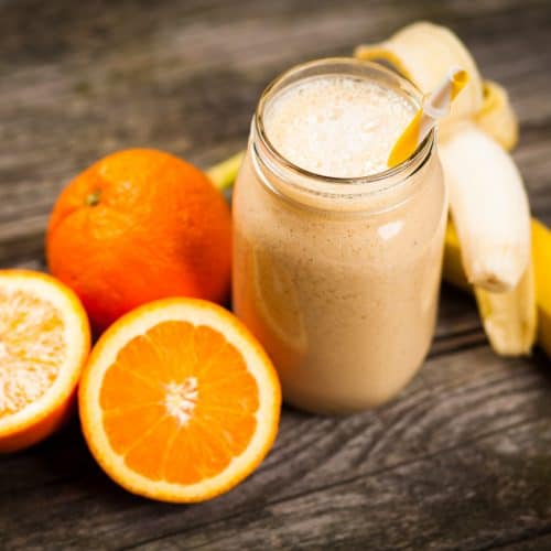 Banana orange smoothie on wooden table