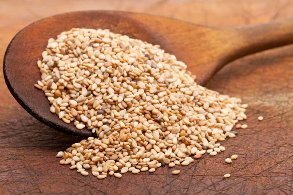 Organic natural sesame seeds on wooden spoon