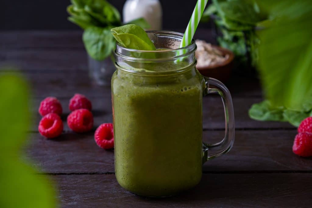 spinach raspberry smoothie with ingredients around