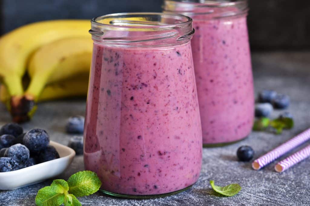 blueberry banana oatmeal smoothie in jars on gray background