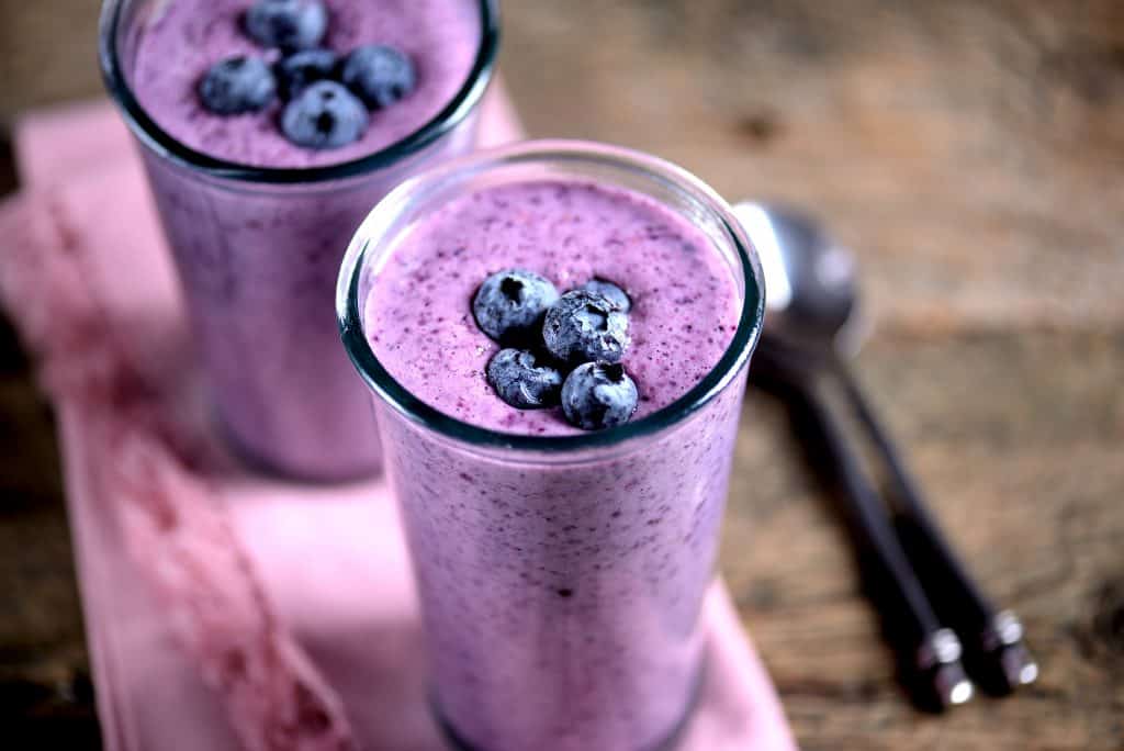 blueberr protein smoothies in glasses on wooden background