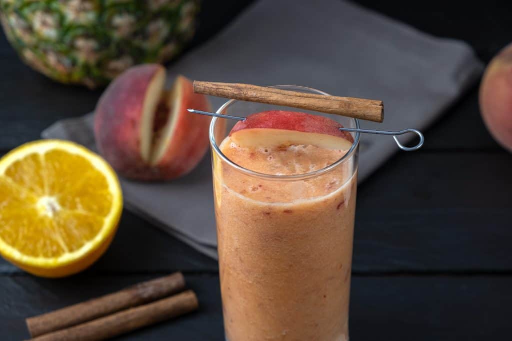 pineapple peach smoothie in glass on dark background