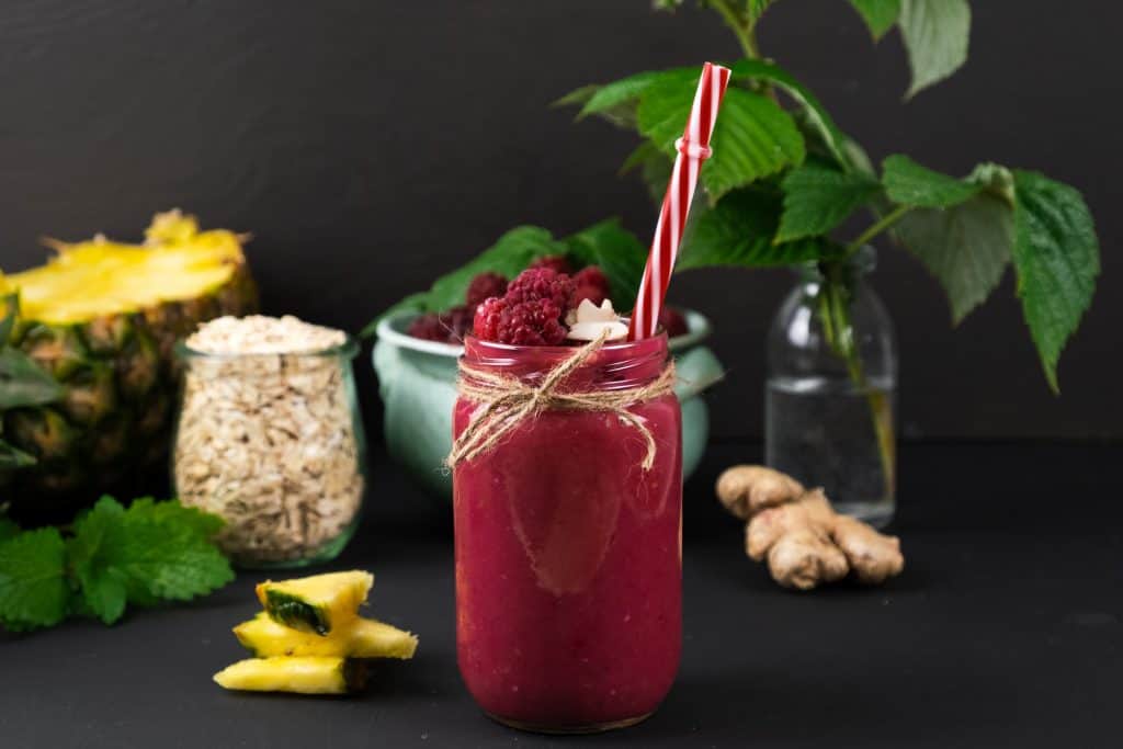 raspberry pineapple smoothie in glass with straw