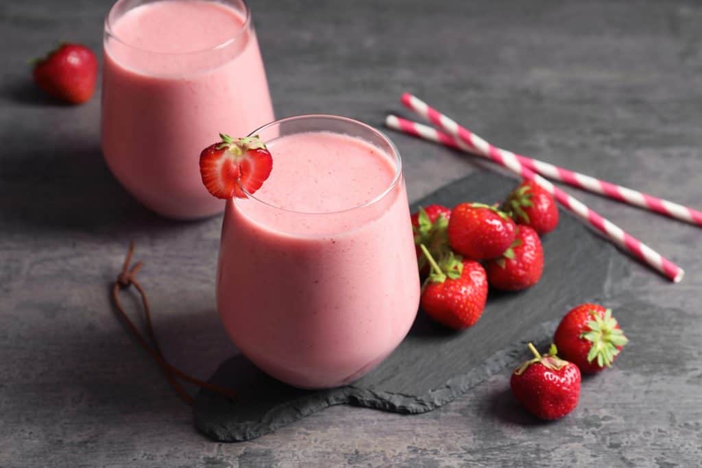 strawberry cheesecake smoothies in glasses on gray background