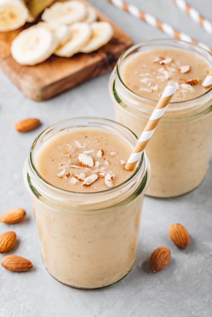 jars of fresh almond milk smoothies with ingredients in background