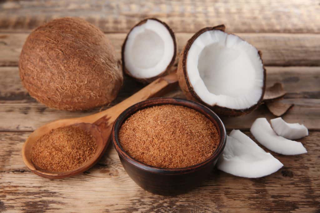 Bowl and spoon of coconut sugar on wooden background