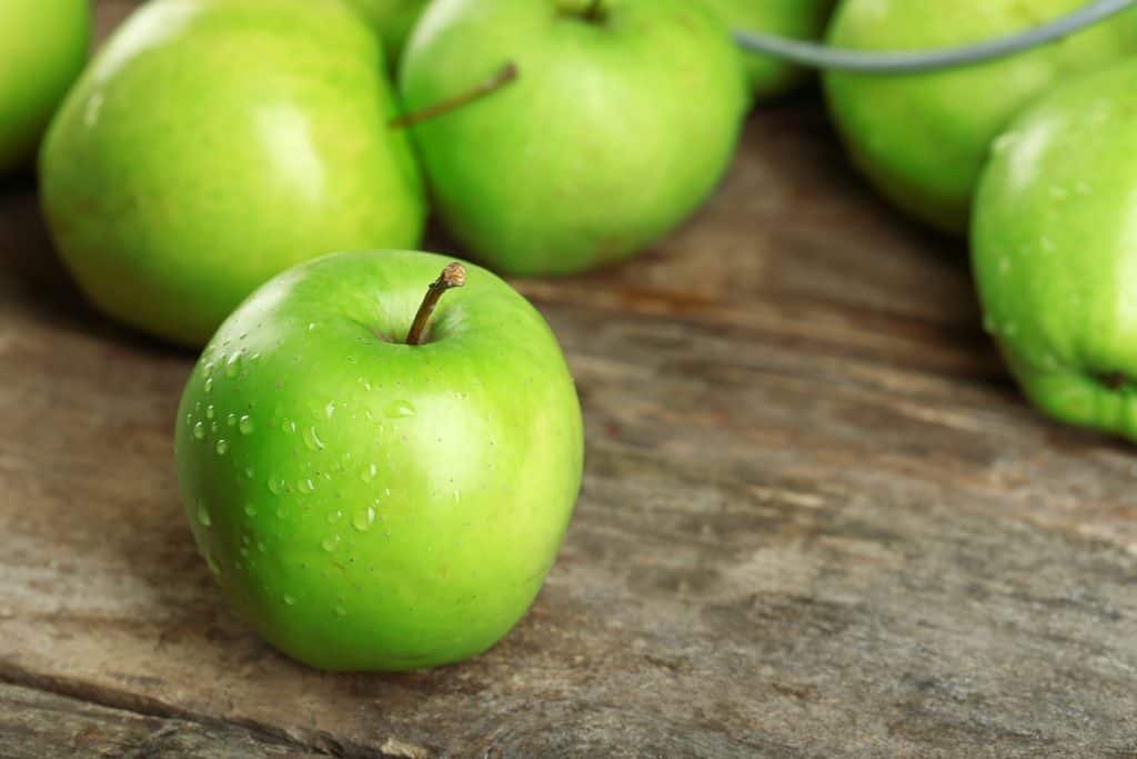 Ripe green apples on wooden table close up